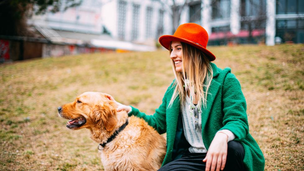 woman-sitting-with-golden-retriever-in-sand
